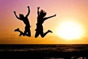 Two people jumping for joy against a setting sun