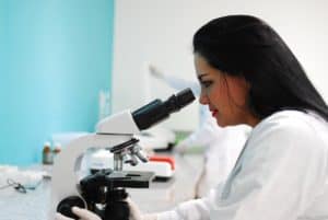 Female researcher looking through microscope