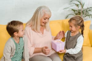 Elderly woman receiving pink gift box from grandchildren 