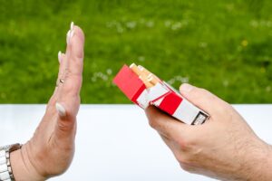 Picture of a hand offering a cigarette to another hand.