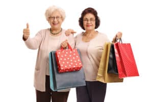 Two elderly women holding several shopping bags
