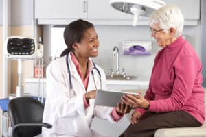 Female medical professional visiting with elderly woman in clinic
