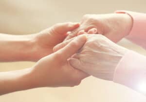 Hands of young person holding hands of elderly person