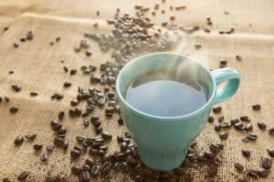 Cup of coffee surrounded by coffee beans