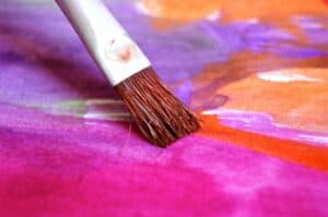 Paint brush on multicolored paint canvas