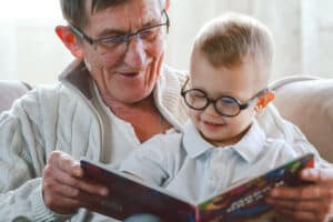 Image of grandpa reading a book to grandson.