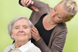 Image of young woman combing elderly woman's hair.