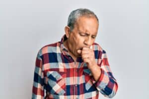 Senior Hispanic man wearing casual clothes feeling unwell and coughing.