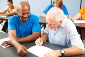 Young man helping an older man in a college class.